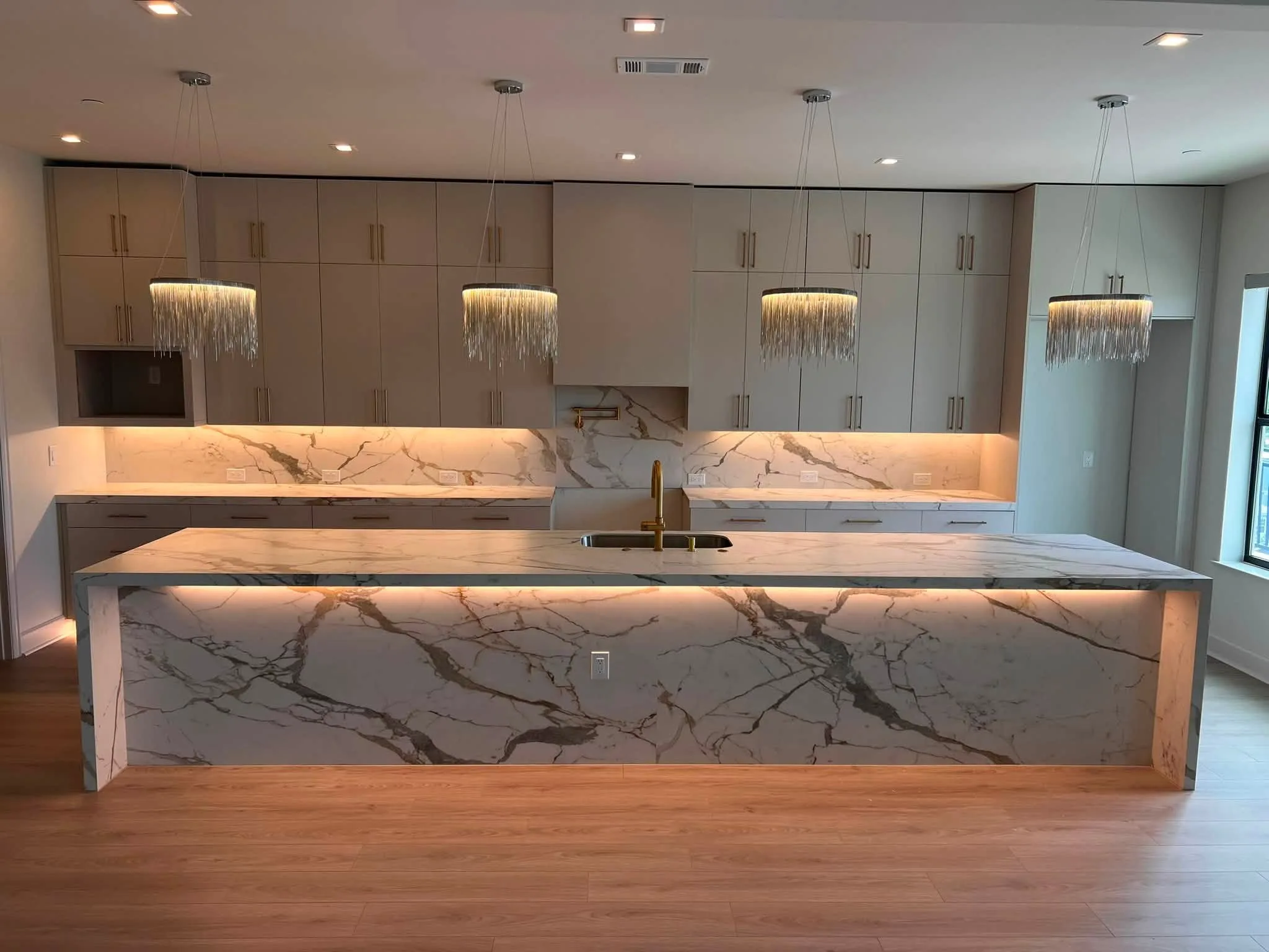 Isla de porcelanato en cascada con salpicadero de losa de altura completa, de Omega Marble & Granite